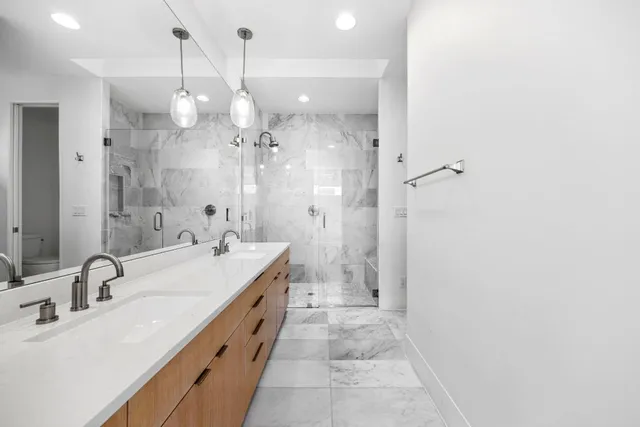 a spacious bathroom with a double vanity sink a large mirror and shower