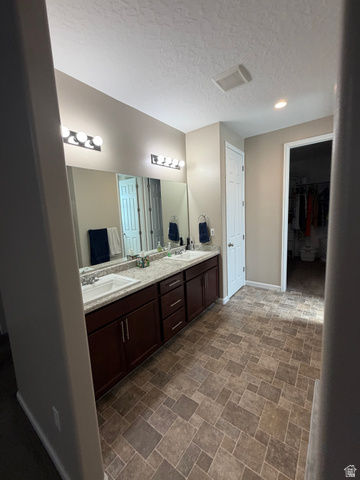 118 Tram Rock Rd. Lake Point, UT 84074 - Photo 16 of 34 Dual vanity featuring white integrated sinks, dark wood cabinetry, and a light speckled countertop