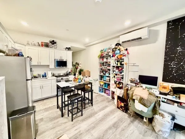 a room with stainless steel appliances kitchen island granite countertop a dining table chairs and a refrigerator