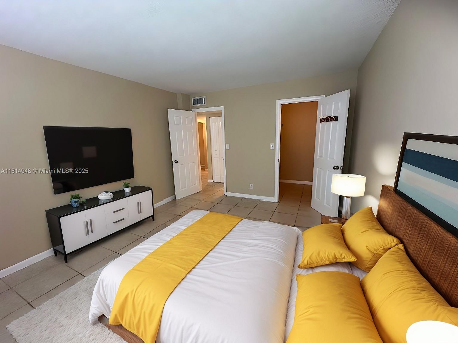 9001 Southwest 77th Avenue, Unit C705 Miami, FL 33156 - Photo 5 of 11 a bedroom with a bed and a flat screen tv