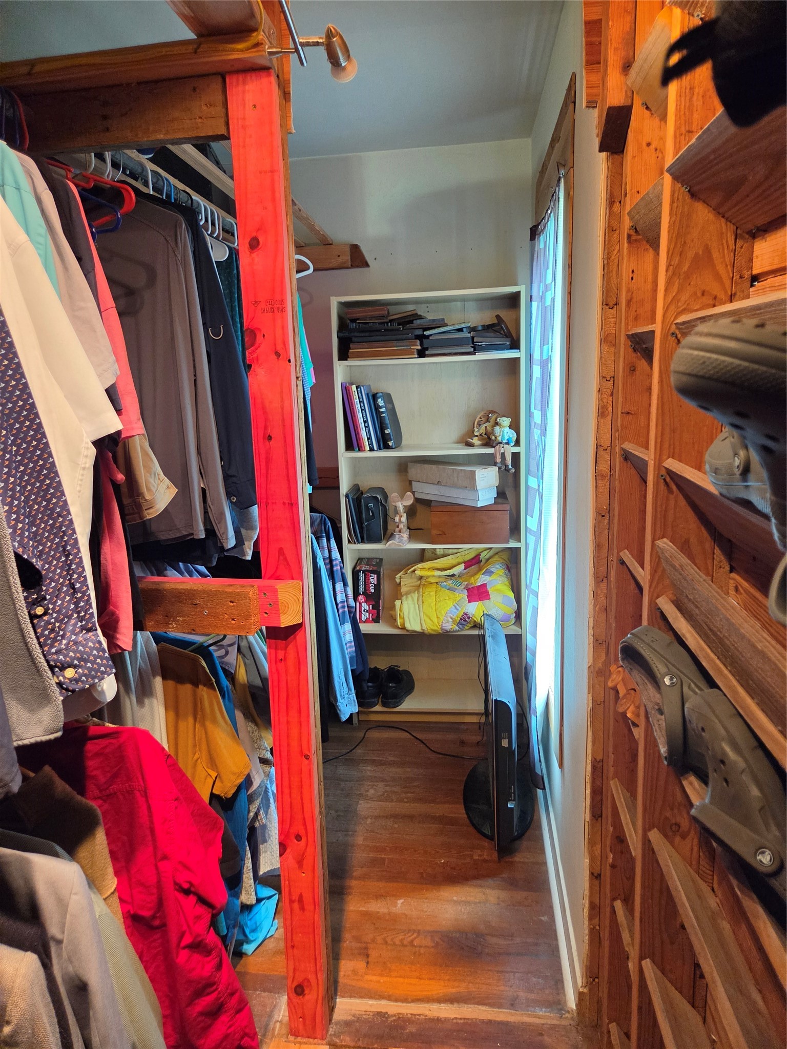 4910 FM 3012 Road Wharton, TX 77488 - Photo 9 of 21 The master bedroom has a narrow walk-in closet featuring wooden shelving and ample hanging space for clothes. It includes built-in shelves for additional storage and natural light from a window on the side.