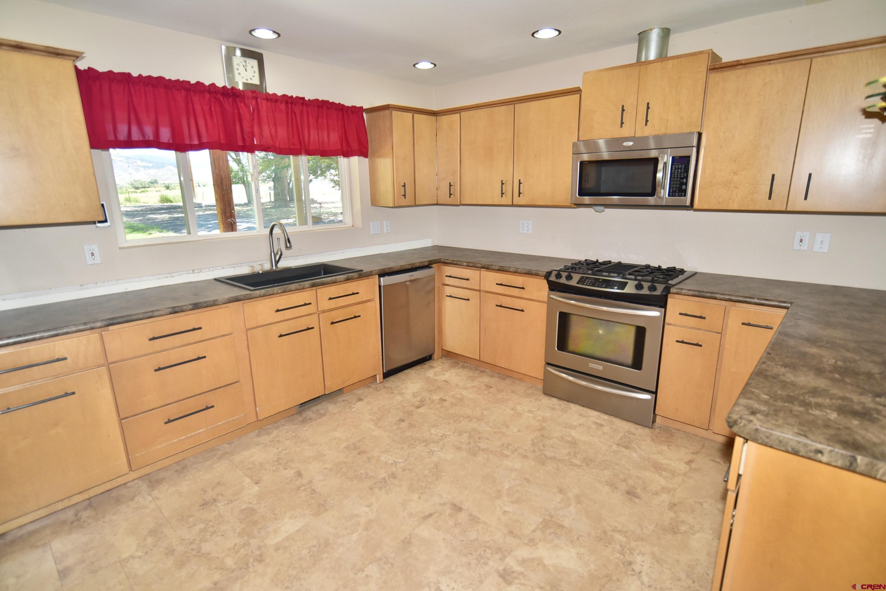 68600 Kinikin Road Montrose, CO 81403 - Photo 8 of 44 a kitchen with stainless steel appliances granite countertop a stove a sink and a microwave