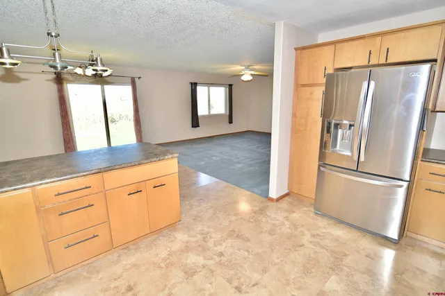 a kitchen with granite countertop a refrigerator a sink and white cabinets
