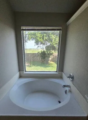 an empty room with a chandelier fan and windows