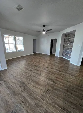 a view of an empty room with a window and wooden floor