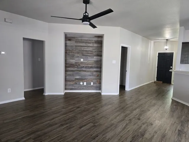 a view of an empty room with wooden floor and a window