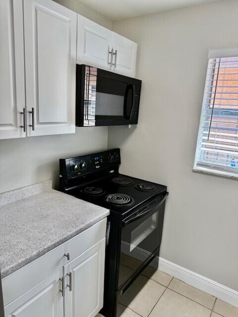 550 Southwest 2nd Avenue, Unit 224 Boca Raton, FL 33432 - Photo 11 of 33 a kitchen with granite countertop white cabinets and black appliances
