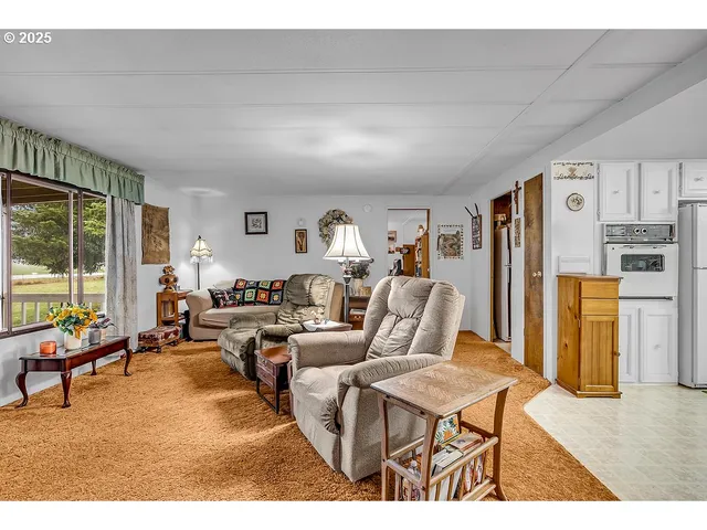 a living room with furniture kitchen view and a large window