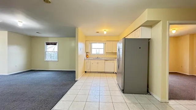 a kitchen with granite countertop a refrigerator and white cabinets