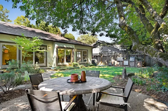 a view of a patio with table and chairs potted plants with large tree