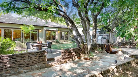 a view of a patio with table and chairs potted plants and large tree