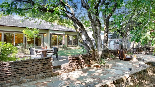 a view of a patio with table and chairs potted plants and large tree