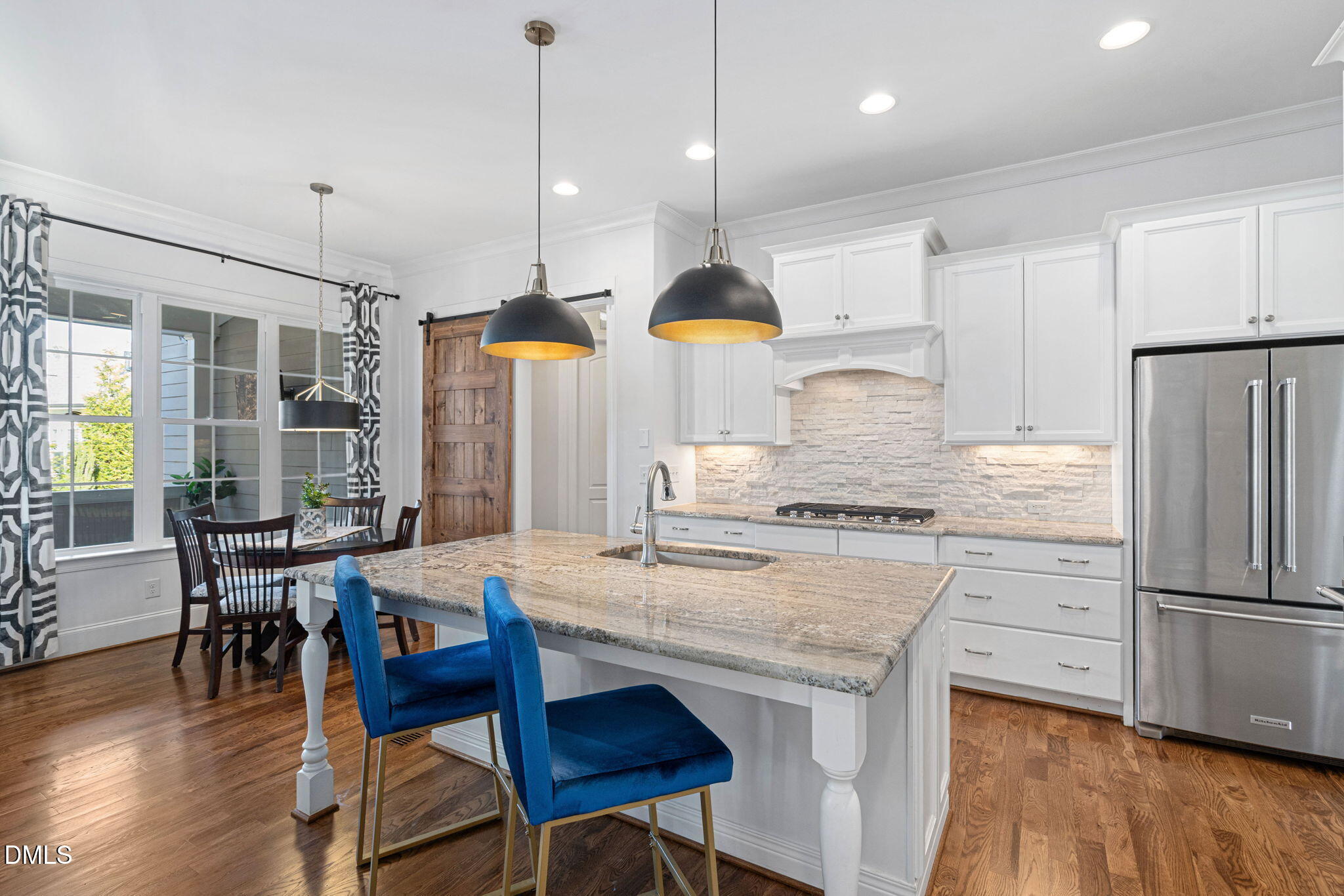2414 Vetrina Way Apex, NC 27502 - Photo 10 of 60 a kitchen with granite countertop a table chairs stove a refrigerator and wooden floor