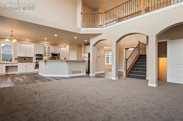 an empty room with windows and chandelier fan