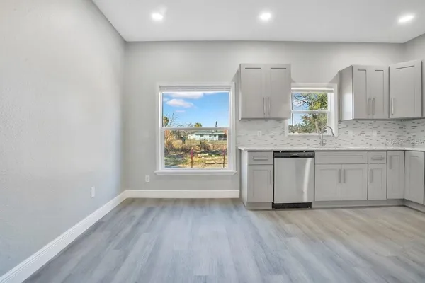 a view of a kitchen with a sink dishwasher a stove and cabinets with wooden floor