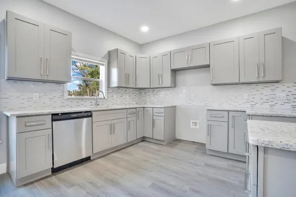 a kitchen with stainless steel appliances granite countertop a stove a sink and white cabinets