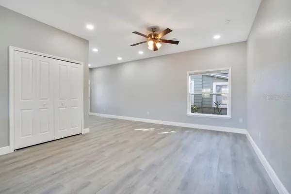 a view of an empty room with wooden floor and a window