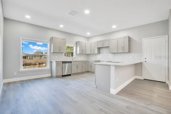 a kitchen with stainless steel appliances granite countertop a white cabinets a sink a stove a refrigerator and island with wooden floor