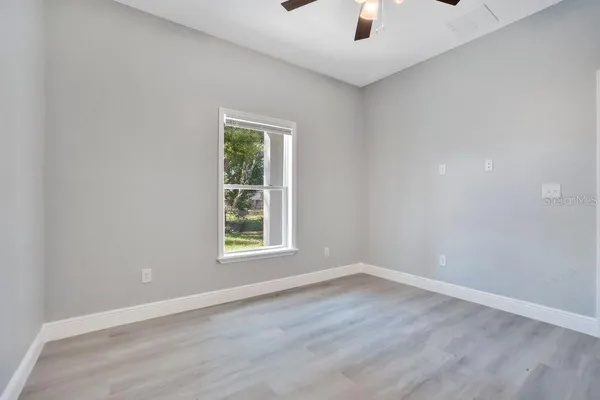 an empty room with a window and a ceiling fan