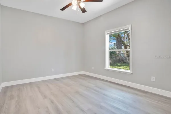 an empty room with a window and a ceiling fan