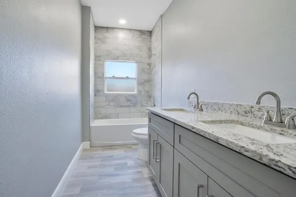 a bathroom with a granite countertop sink a toilet and shower