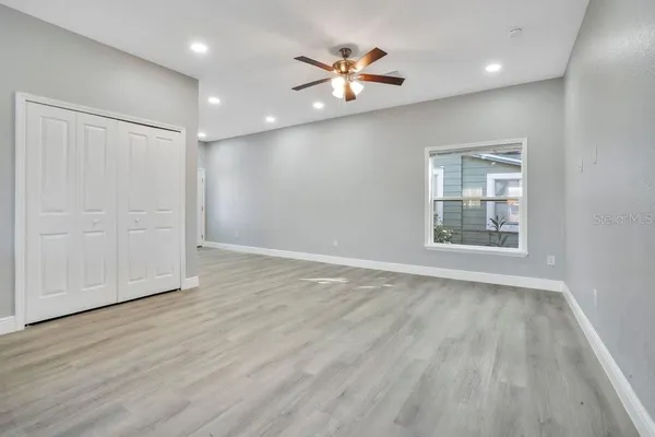 a view of an empty room with a window and wooden floor