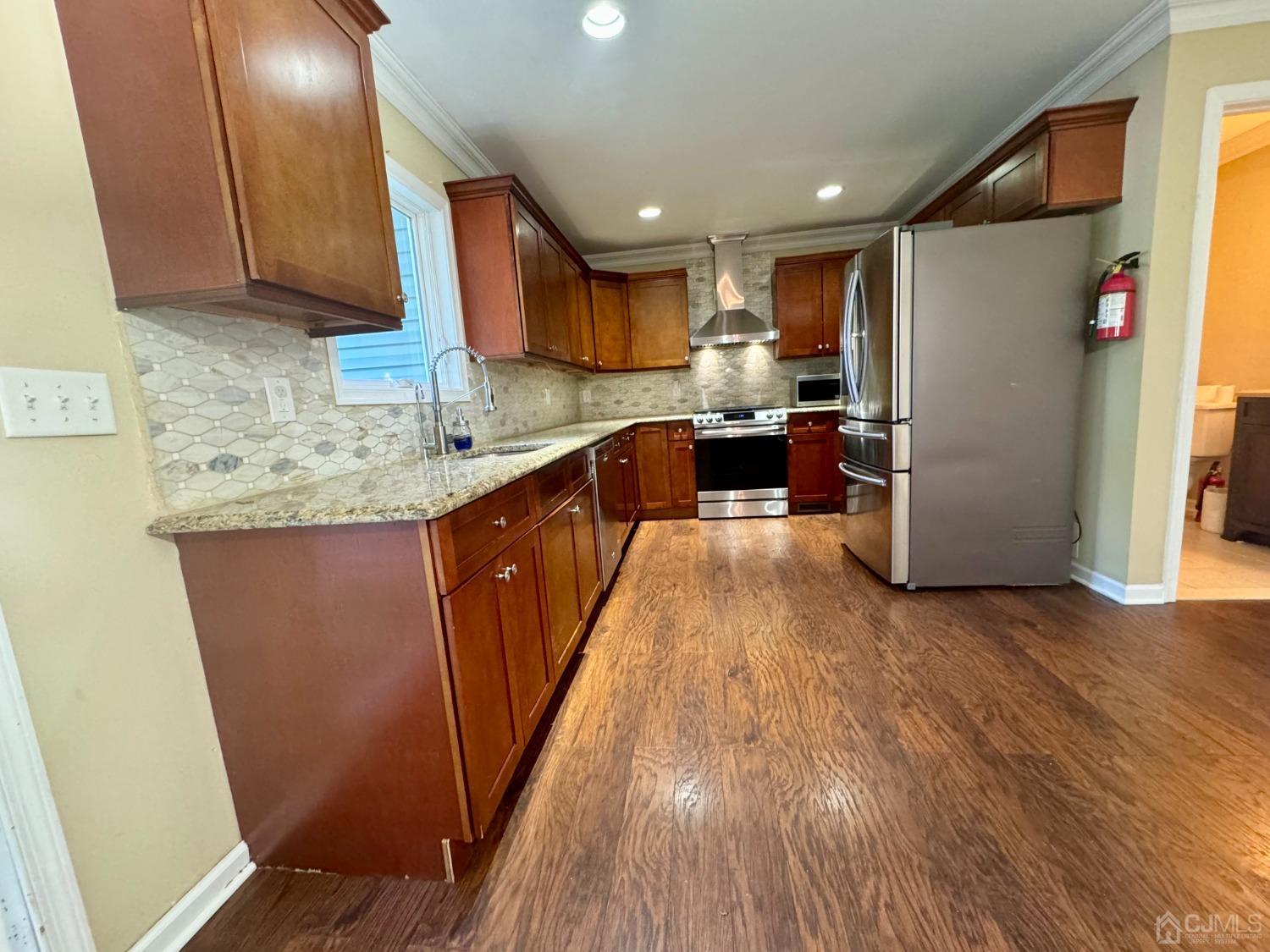 14 Baxter Road Edison, NJ 08817 - Photo 10 of 16 a kitchen with stainless steel appliances granite countertop a refrigerator a sink dishwasher a stove and white countertops with wooden floor