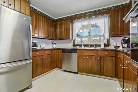 a kitchen with stainless steel appliances granite countertop a refrigerator a sink dishwasher and wooden cabinets with wooden floor
