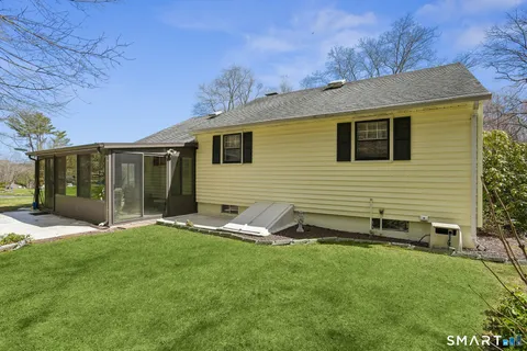 a backyard of a house with table and chairs and large trees