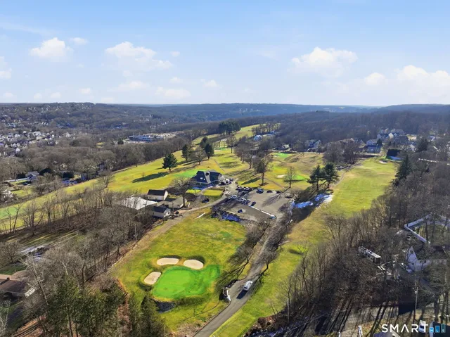 an aerial view of a pool with a yard and mountain view in back