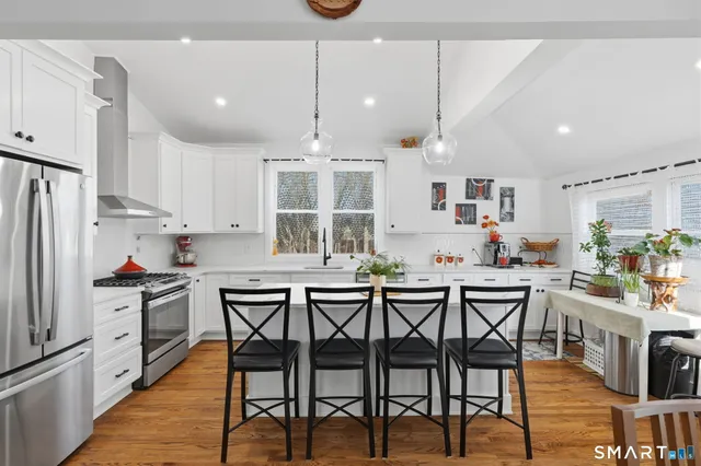 a kitchen with stainless steel appliances a dining table chairs stove and white cabinets
