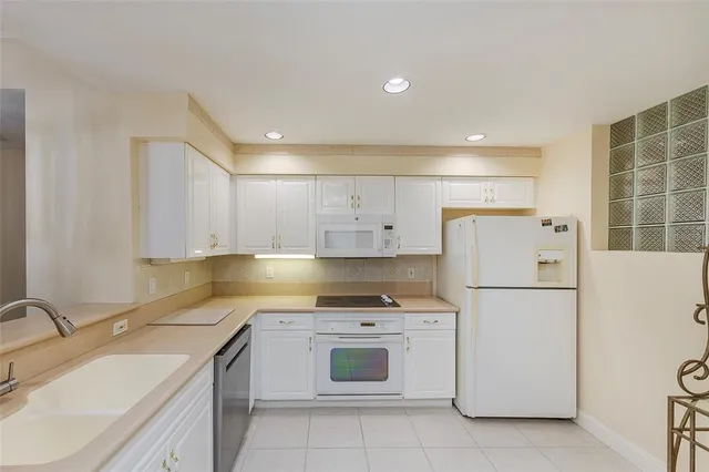 a kitchen with a refrigerator a stove a sink and white cabinets