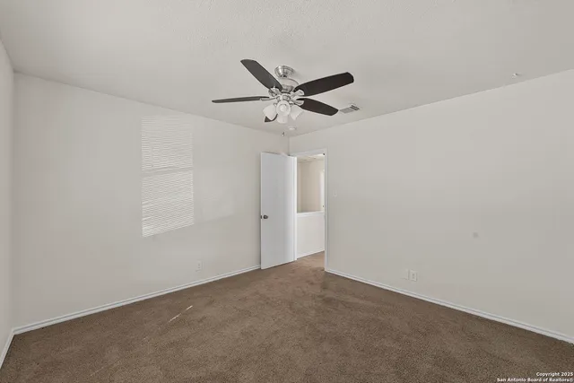an empty room with a window and a ceiling fan