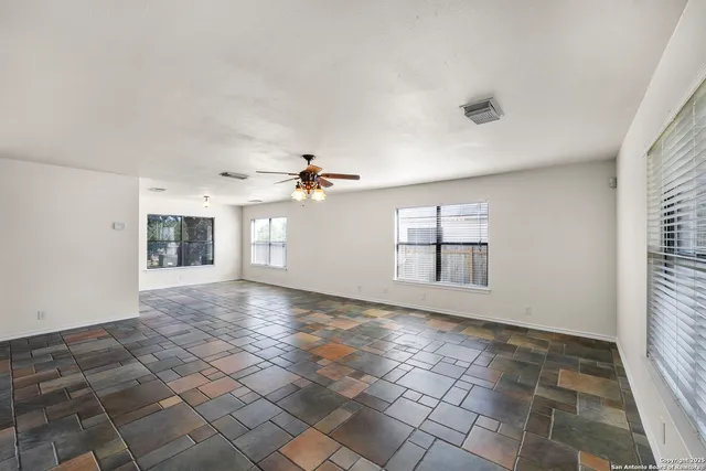 an empty room with windows and chandelier fan