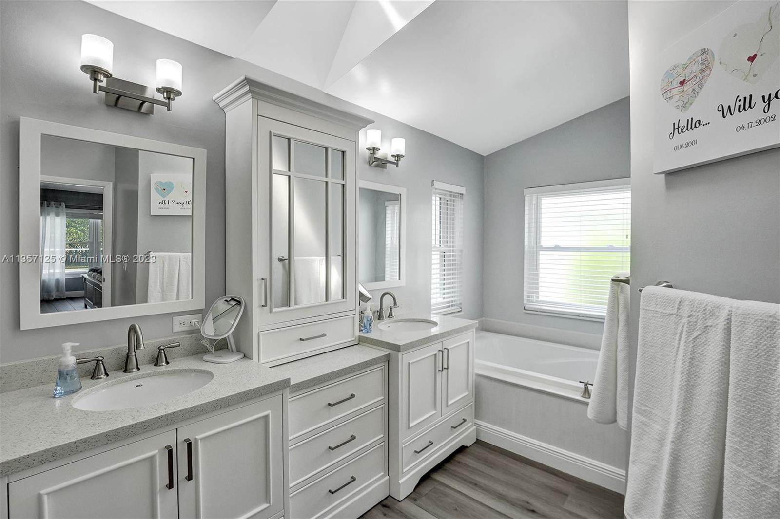 22190 Appleton Drive Boca Raton, FL 33428 - Photo 17 of 41 a bathroom with double vanity sink a mirror a window and a bathtub
