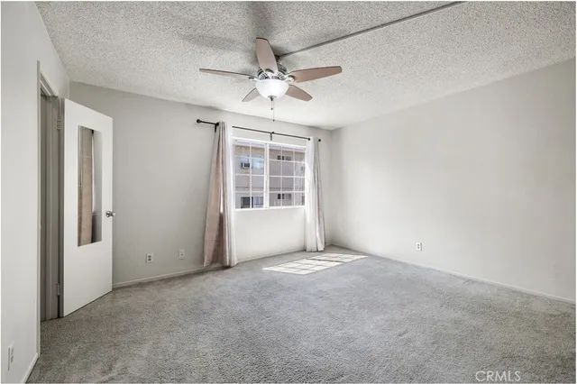 an empty room with windows and fan