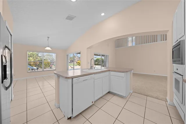 a view of a kitchen with refrigerator and white cabinets