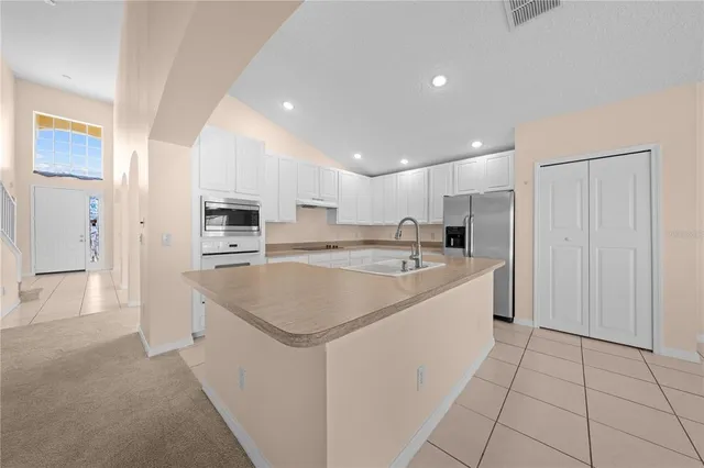 an empty room with chandelier fan and windows