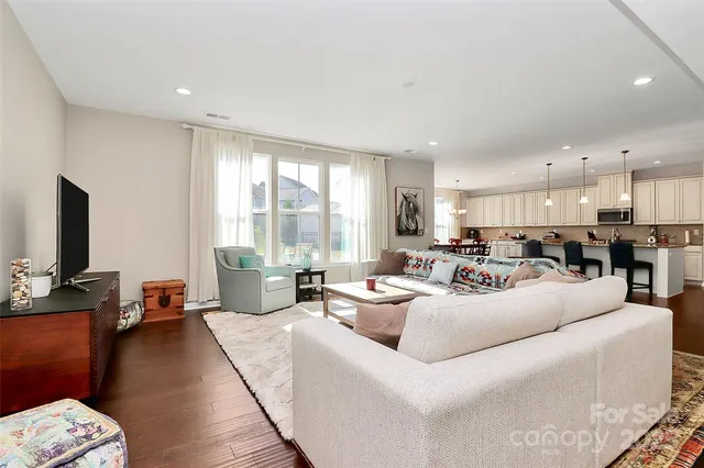 a living room with furniture kitchen view and a large window