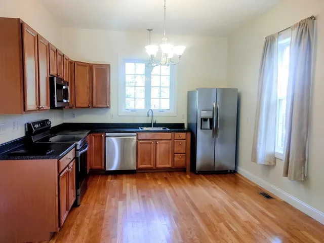 a kitchen with granite countertop a refrigerator and wooden floors
