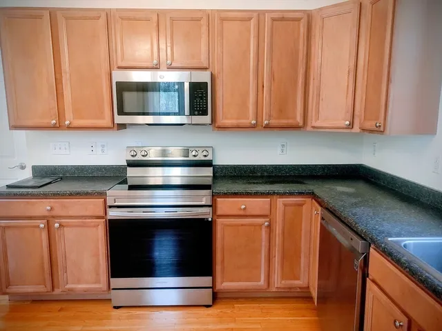 a kitchen with stainless steel appliances granite countertop wooden cabinets a stove and a granite counter top