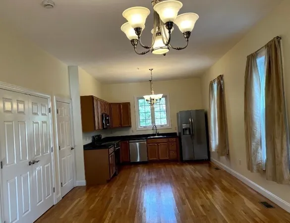 a kitchen with stainless steel appliances granite countertop a refrigerator a stove top oven a sink dishwasher and wooden floor