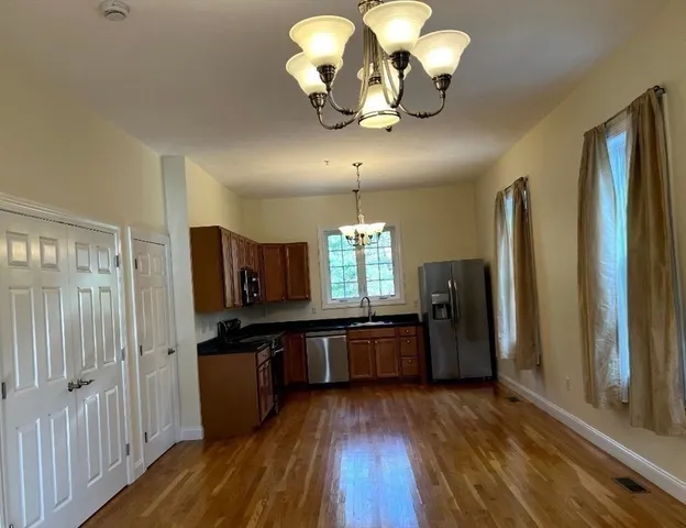 a kitchen with stainless steel appliances granite countertop a refrigerator a stove top oven a sink dishwasher and wooden floor