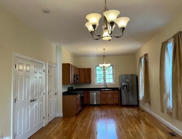a view of a kitchen center island wooden floor and stainless steel appliances