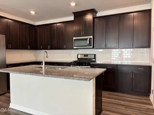 a kitchen with stainless steel appliances granite countertop a sink a stove a refrigerator and cabinets