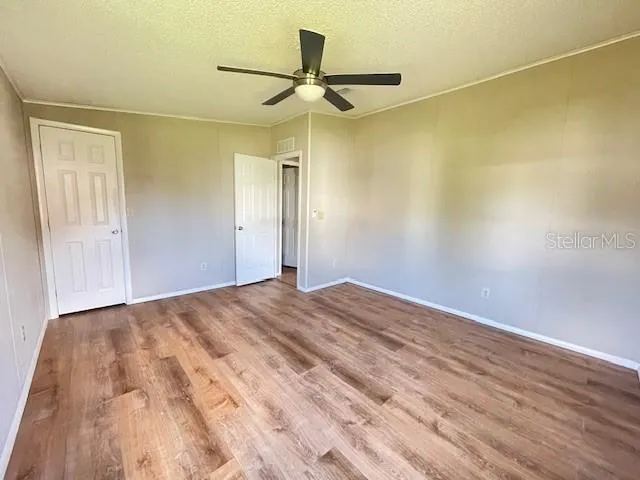 a view of a big room with wooden floor and a ceiling fan