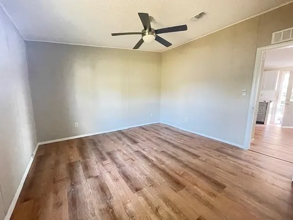 a view of a room with wooden floor and a ceiling fan