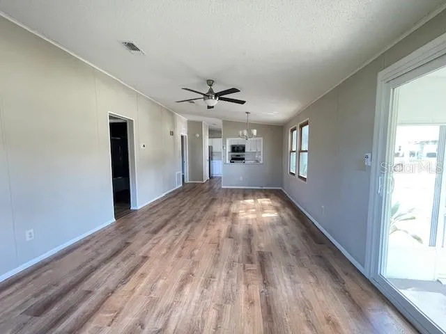 a view of empty room with wooden floor and fan