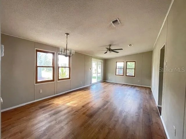 a view of empty room with wooden floor and fan