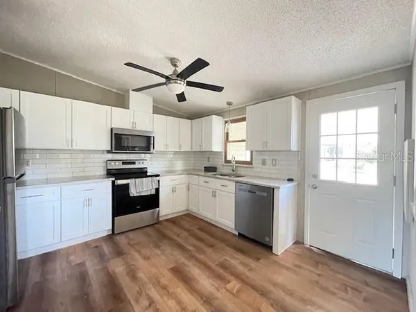 a kitchen with granite countertop white cabinets and white appliances